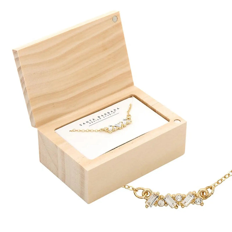 Gold treasure box necklace with crystal accents in a wooden box jewelry display