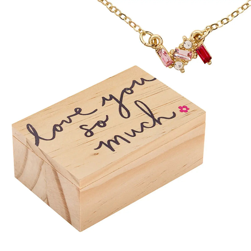Gold necklace with pink and red gemstones in a wooden treasure chest box