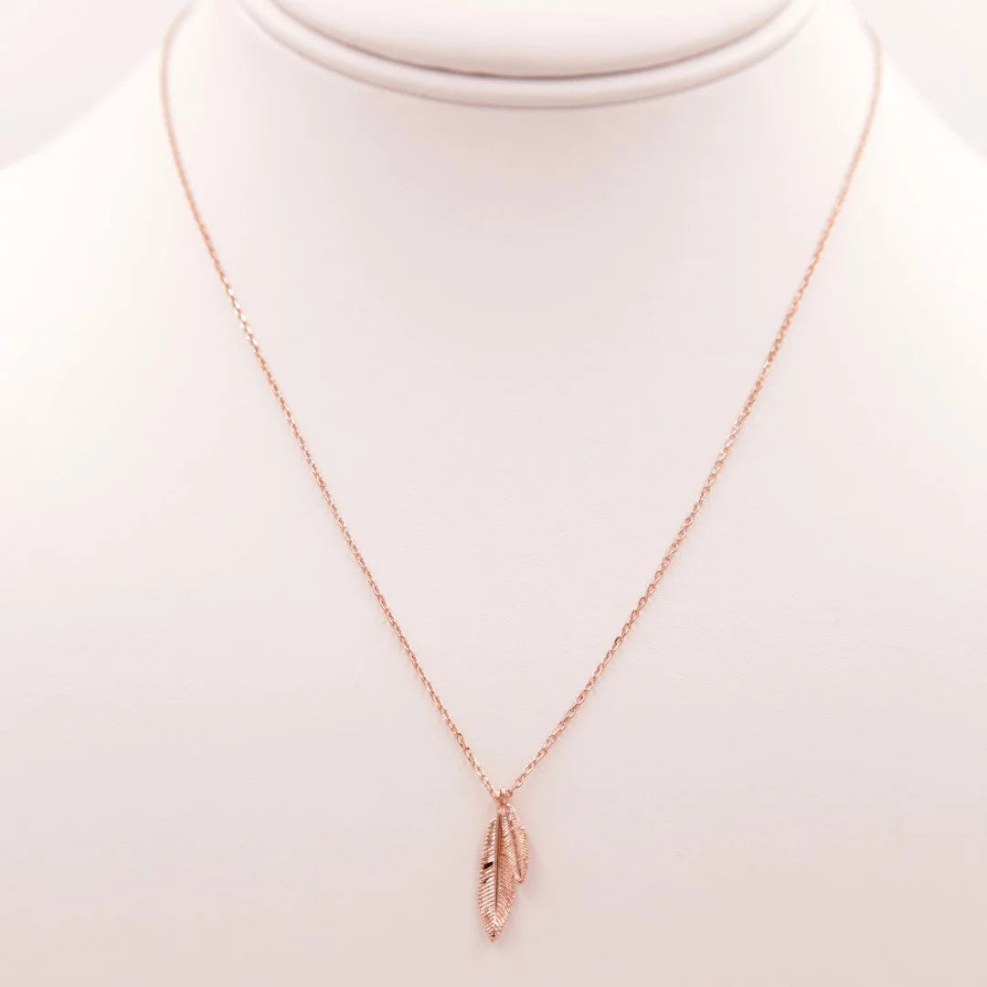 Gold feather necklace with a delicate rose gold charm for bohemian girls