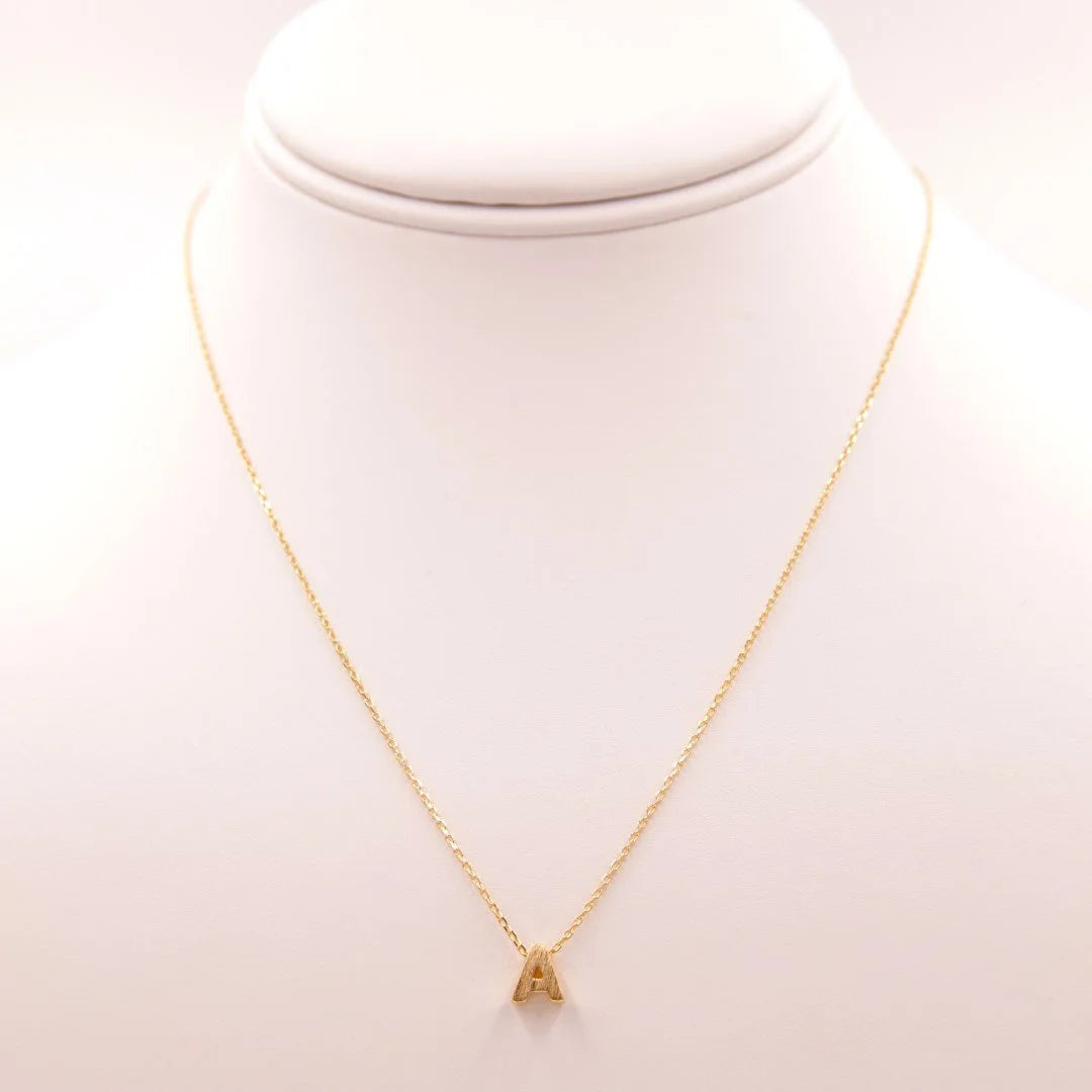 Gold necklace with a triangle pendant from Daisy Lane’s dainty initial collection