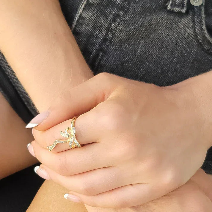Gold-toned tied bow ribbon ring with pave-set clear stones for elegant jewelry style