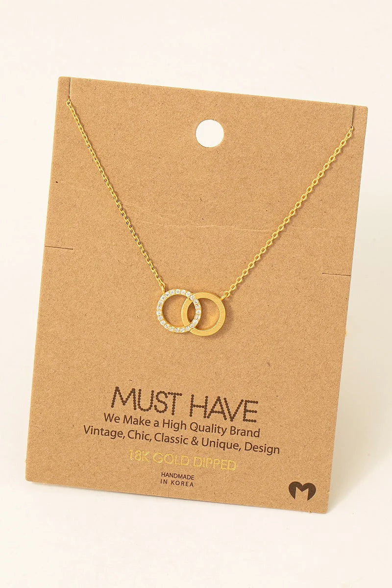 Gold-toned interlocking circles pendant necklace displayed on a brown card