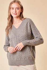 Gray cable-knit v-neck sweater featuring braided patterns, ideal for women’s boho chic clothing