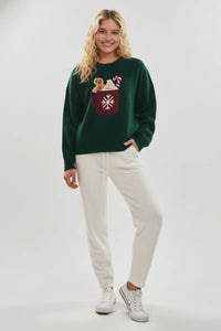 Green gingerbread graphic sweater with white drawstring pants and sneakers