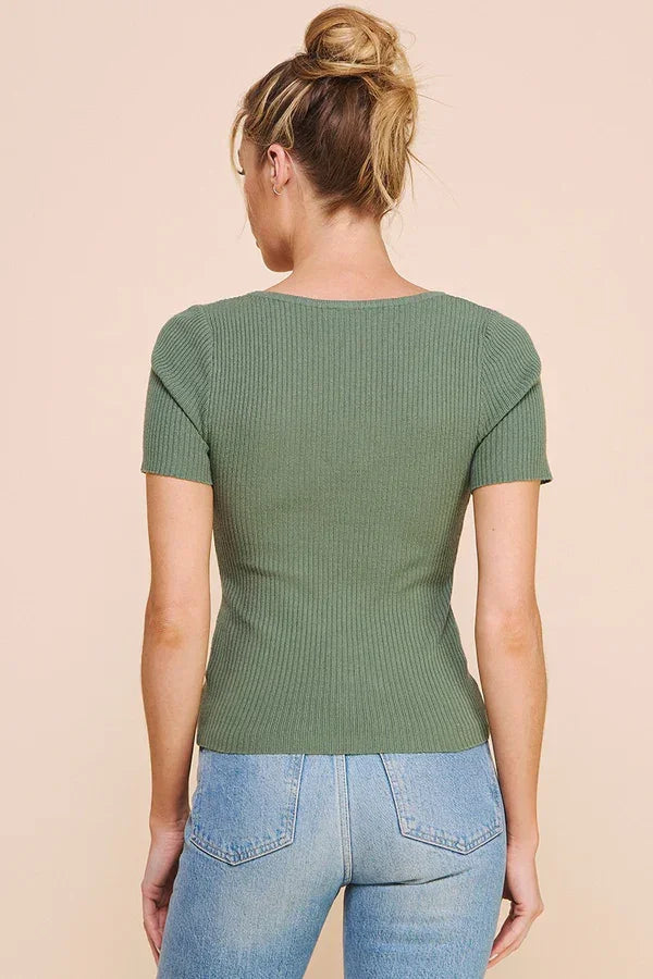 Green short sleeve ribbed fine gauge top worn by a person with blonde hair in a bun