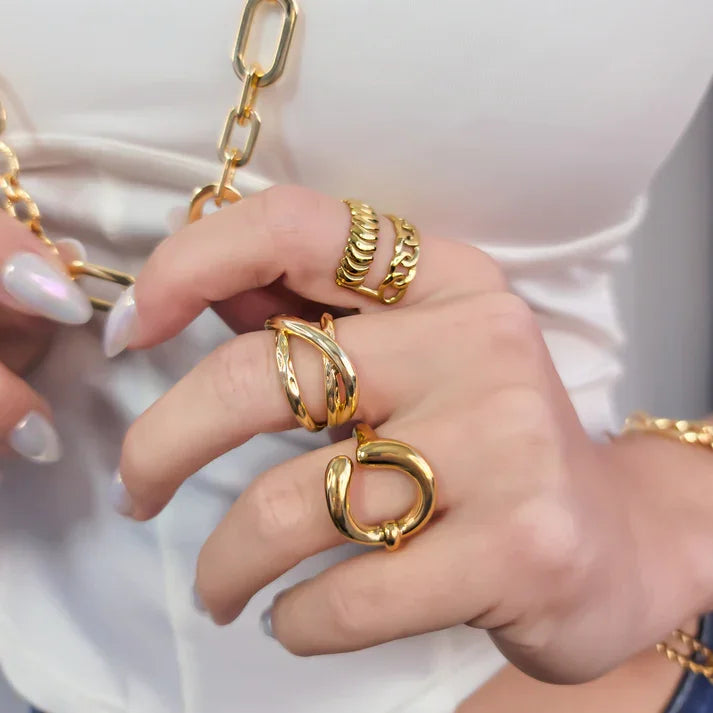 Hand wearing multiple gold rings including a double cross ring and cross ring adjustable