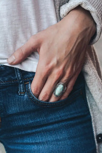 Hand in jeans pocket displaying the vintage turquoise ring with a turquoise gemstone