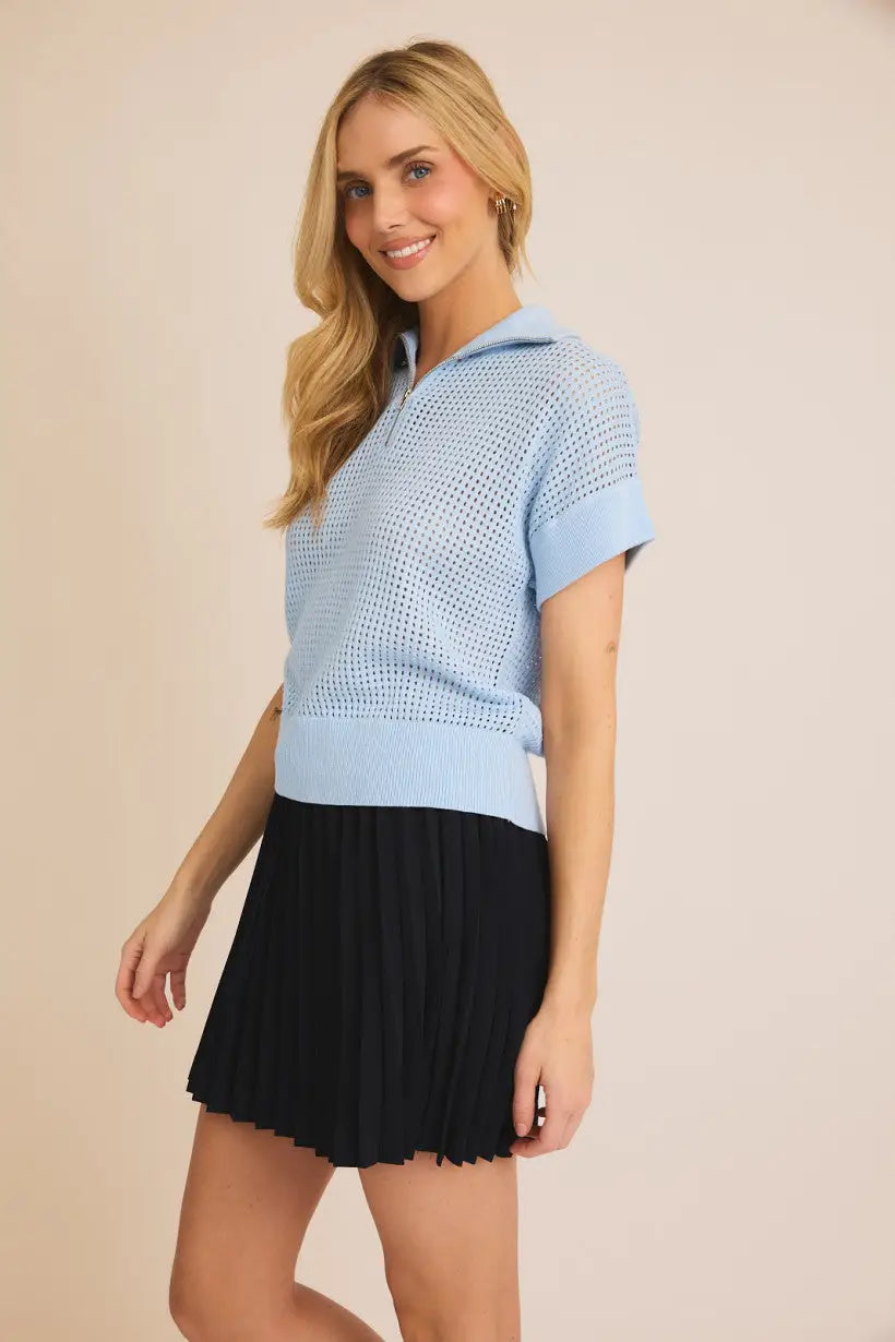 Light blue knit polo shirt with black pleated skirt in women’s boho chic clothing at Shop Daisy