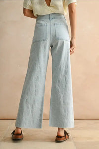 Light blue wide-leg denim pants with floral stitch pattern, perfect for women’s boho chic clothing