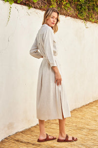 Light-colored maxi shirt dress with vertical stripes, worn by a woman in a stylish pose