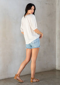Light-colored floral puff sleeve button front top paired with distressed denim shorts and brown gladiator sandals