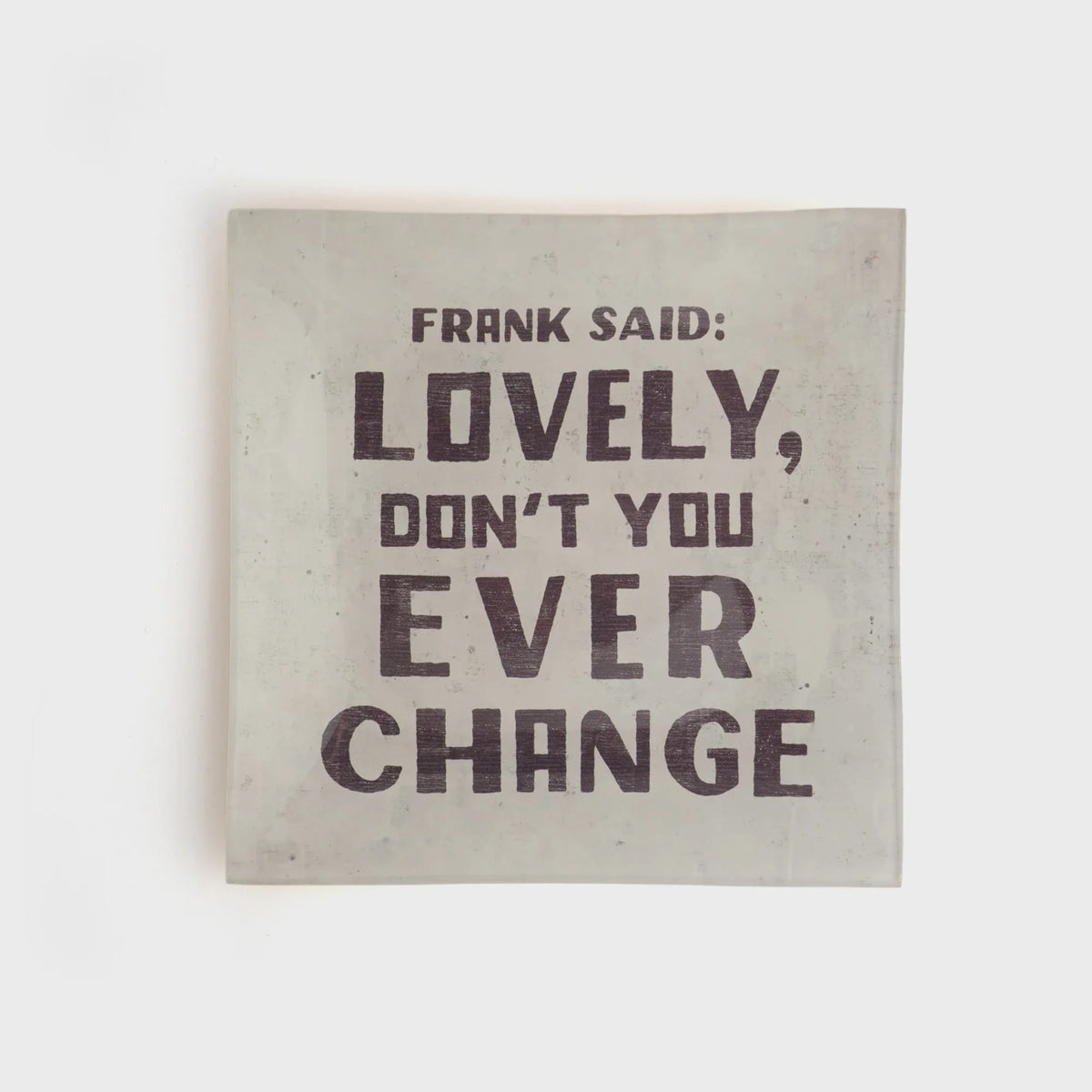 Light-colored small square decoupage plate with bold dark text for decorative display