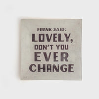 Light-colored small square decoupage plate with bold dark text for decorative display