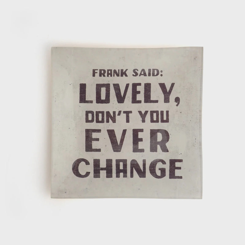 Light-colored small square decoupage plate with bold dark text for decorative display
