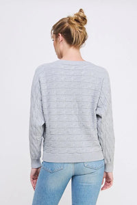 Light gray long sleeve cable knit sweater showcased on a person with blonde hair in a bun