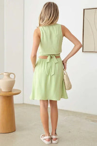 Light green sleeveless flowy dress with tied waist and knee-length skirt for boho style