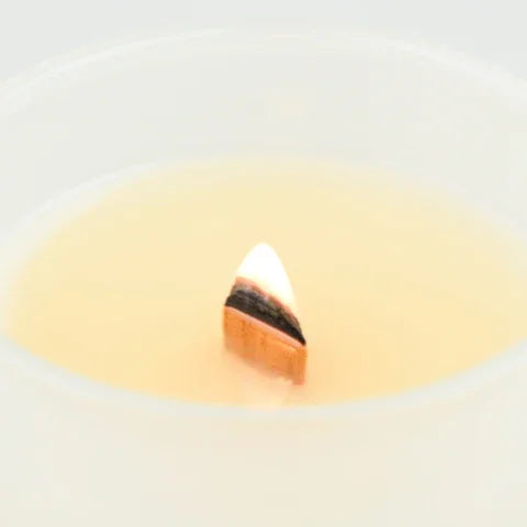 Lit candle wick burning with a warm flame from PATCHOULI OUD WOODEN WICK CANDLE