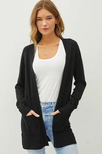 Long black knit sweater cardigan over white top and blue jeans, essential open style