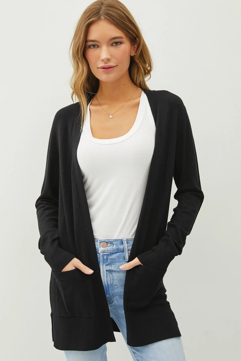 Long black knit sweater cardigan over white top and blue jeans, essential open style