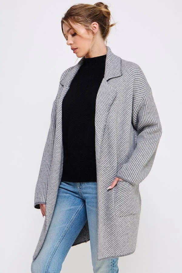 Long gray knit cardigan over a black top and blue jeans, featuring diagonal striped plush design