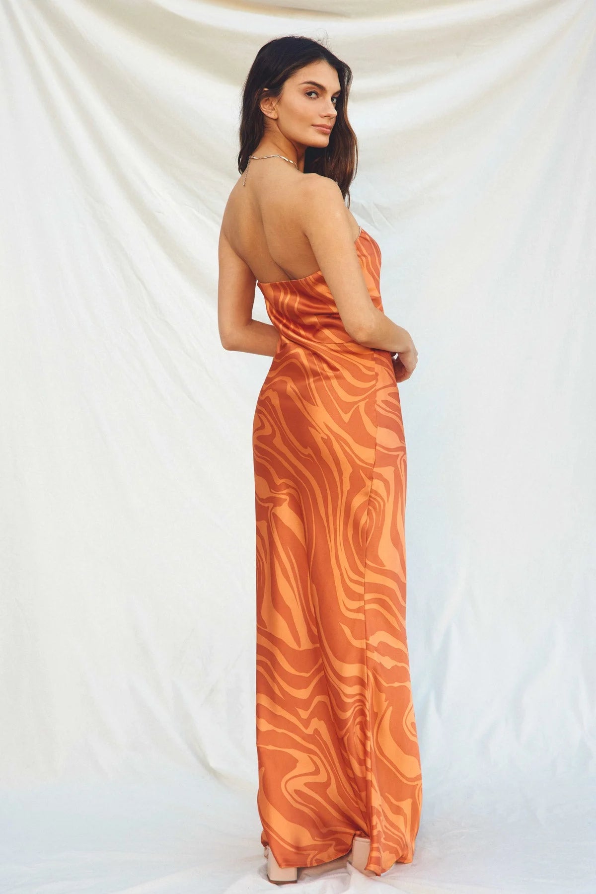 Woman in a long orange maxi dress with a swirling pattern, showcasing boho style