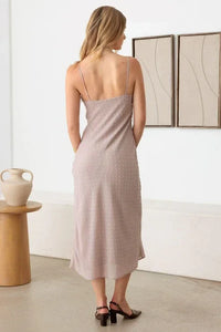 Long pale pink polka dot midi dress with spaghetti straps worn by a woman