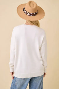 White long-sleeved crewneck sweater with pumpkin truck embroidered patchwork design