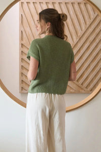 Women’s boho chic outfit featuring a green knit mock neck sweater and cream wide-leg pants