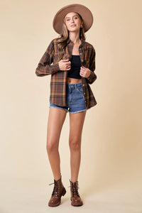 Model showcasing a brown plaid button-down oversized shirt from Shop Daisy’s women’s boho chic clothing