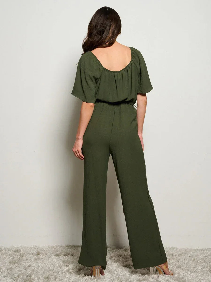 Olive green boho jumpsuit with wide-leg pants and fluttery short sleeves, cinched at waist