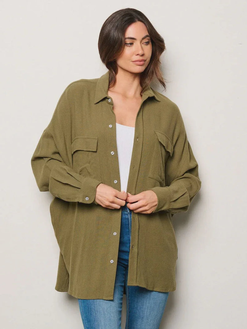 Olive green long sleeve button-up oversized shirt styled over a white top and blue jeans