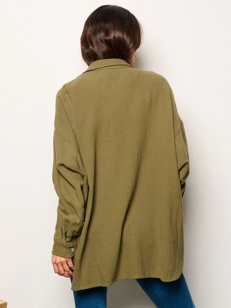 Olive green oversized blazer worn over blue jeans with long sleeve button details