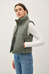 Olive green puffer vest worn over a white long-sleeved top, ideal for boho styles