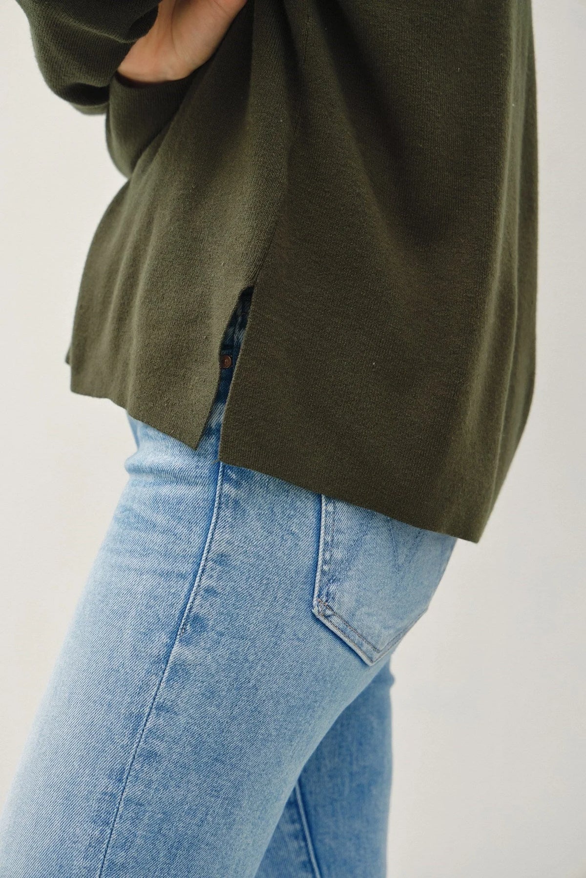 Olive green relaxed v-neck sweater with center seam over light blue jeans, boho style