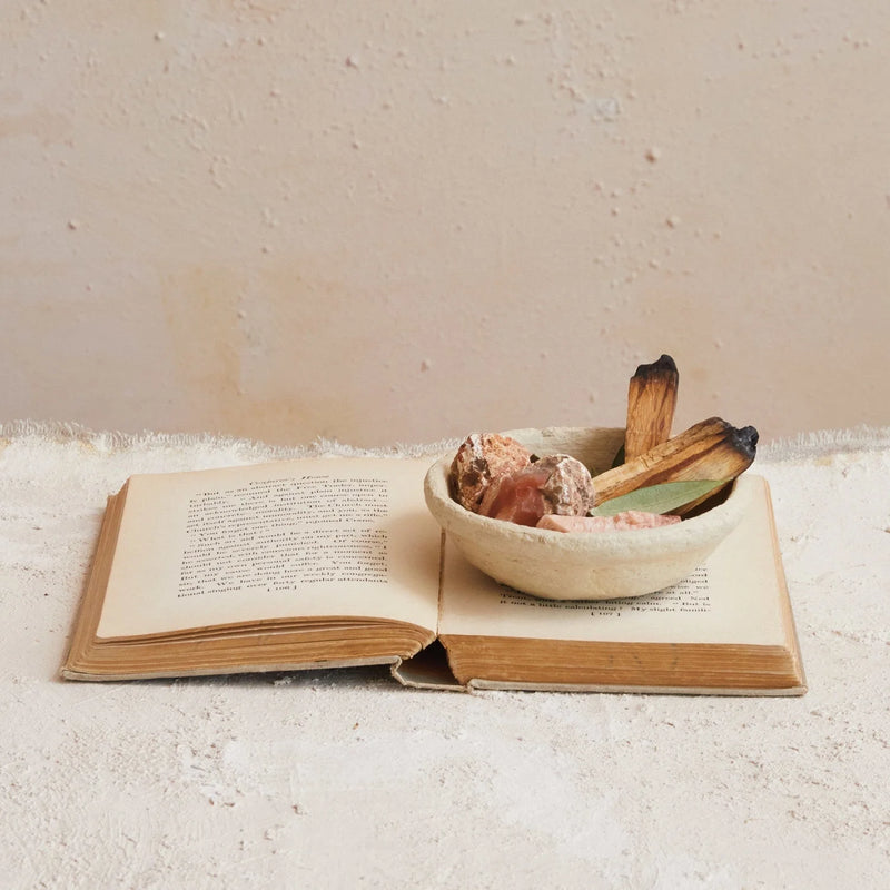 Open book with handmade paper mache bowl filled with food on its pages