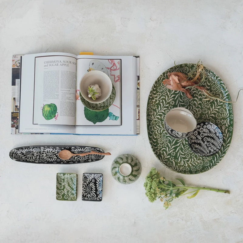 Stoneware dish with botanical wax relief featuring open cookbook with tropical fruit recipe