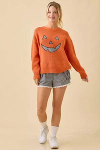 Orange pumpkin face patchwork sweater with black and white gingham face design