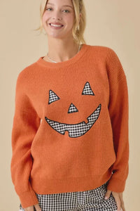 Orange knit Halloween sweater featuring pumpkin face patchwork and festive face patchwork design