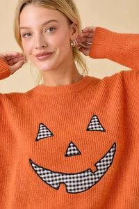 Orange knit sweater with pumpkin face patchwork and black and white gingham face design