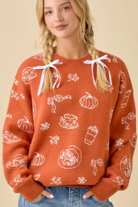 Orange pumpkin spice printed sweater with white autumn patterns and decorative bows
