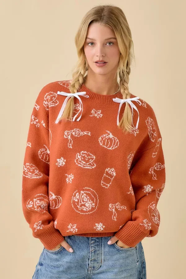 Orange pumpkin spice printed sweater with white autumn patterns and shoulder ribbons