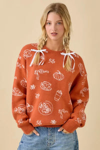Orange pumpkin spice printed sweater with white autumn patterns and shoulder ribbons