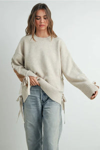 Cream-colored oversized crew neck long sleeve pullover sweater with tie details on sleeves