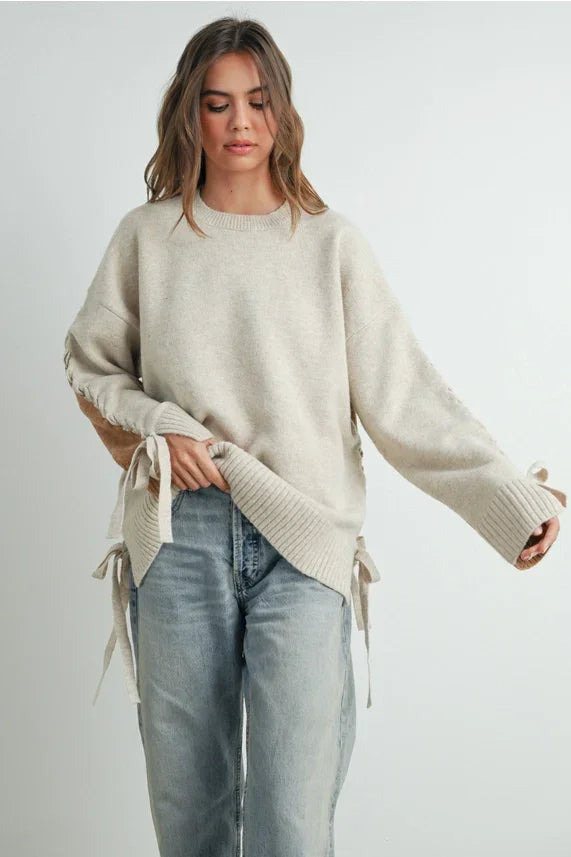 Cream-colored oversized crew neck long sleeve pullover sweater with tie details on sleeves