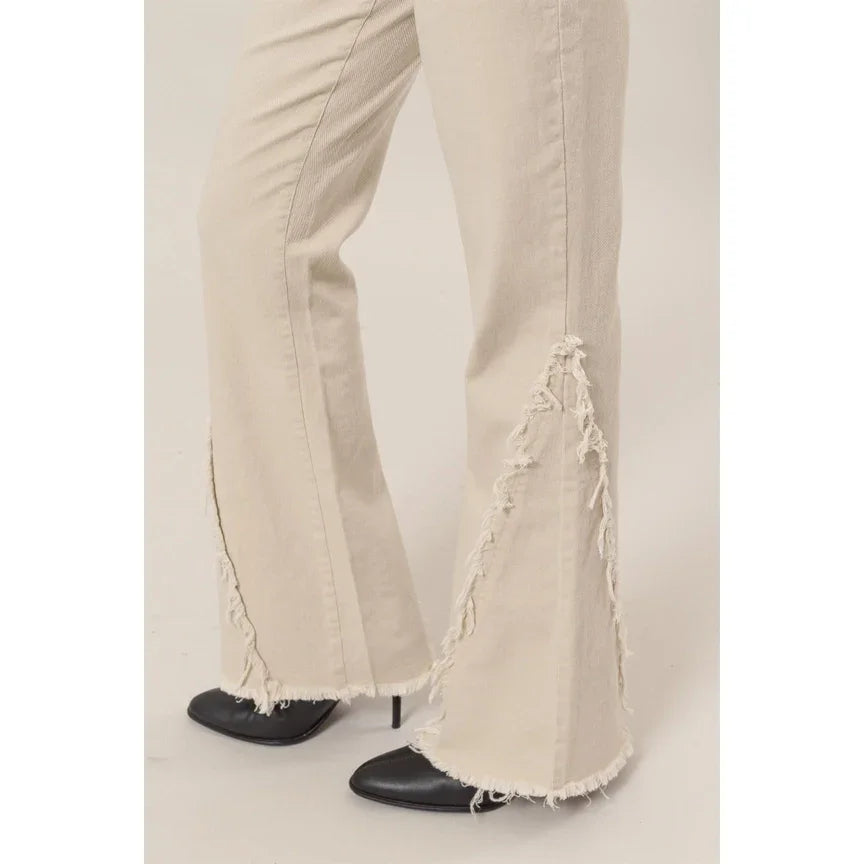 Cream-colored washed twill distressed flare pants with frayed hems over black shoes