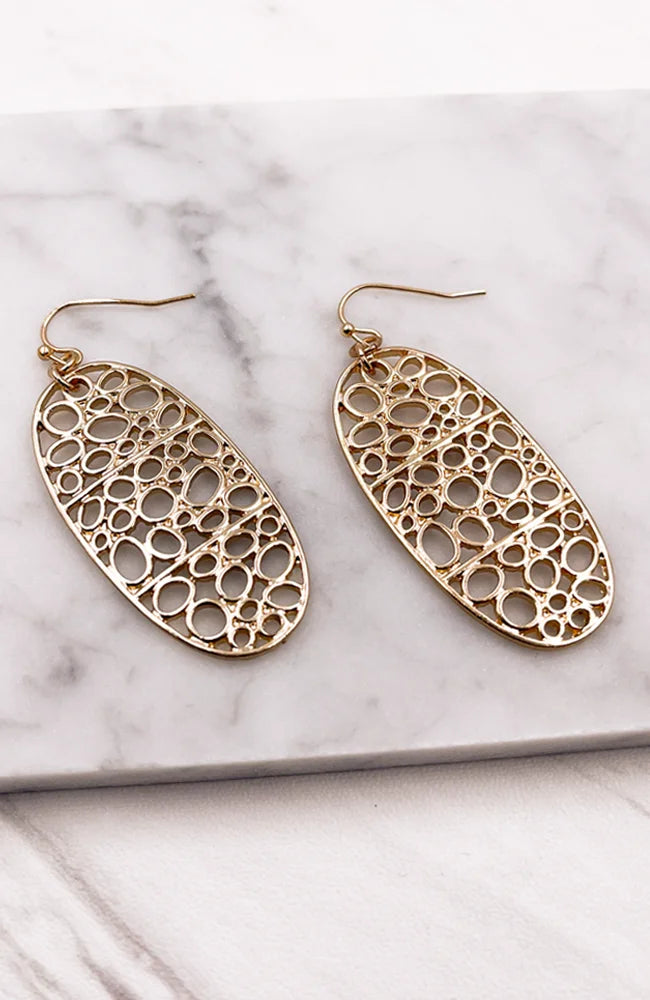 Gold bubbles oval earrings with circular design displayed on a marble surface