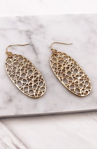 Gold bubbles oval earrings with circular design displayed on a marble surface