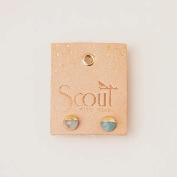 Pair of round stone stud earrings on peach-colored branded packaging card