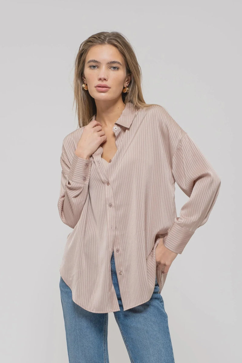 Pale pink satin pinstripe button-up top styled over blue jeans for a chic look