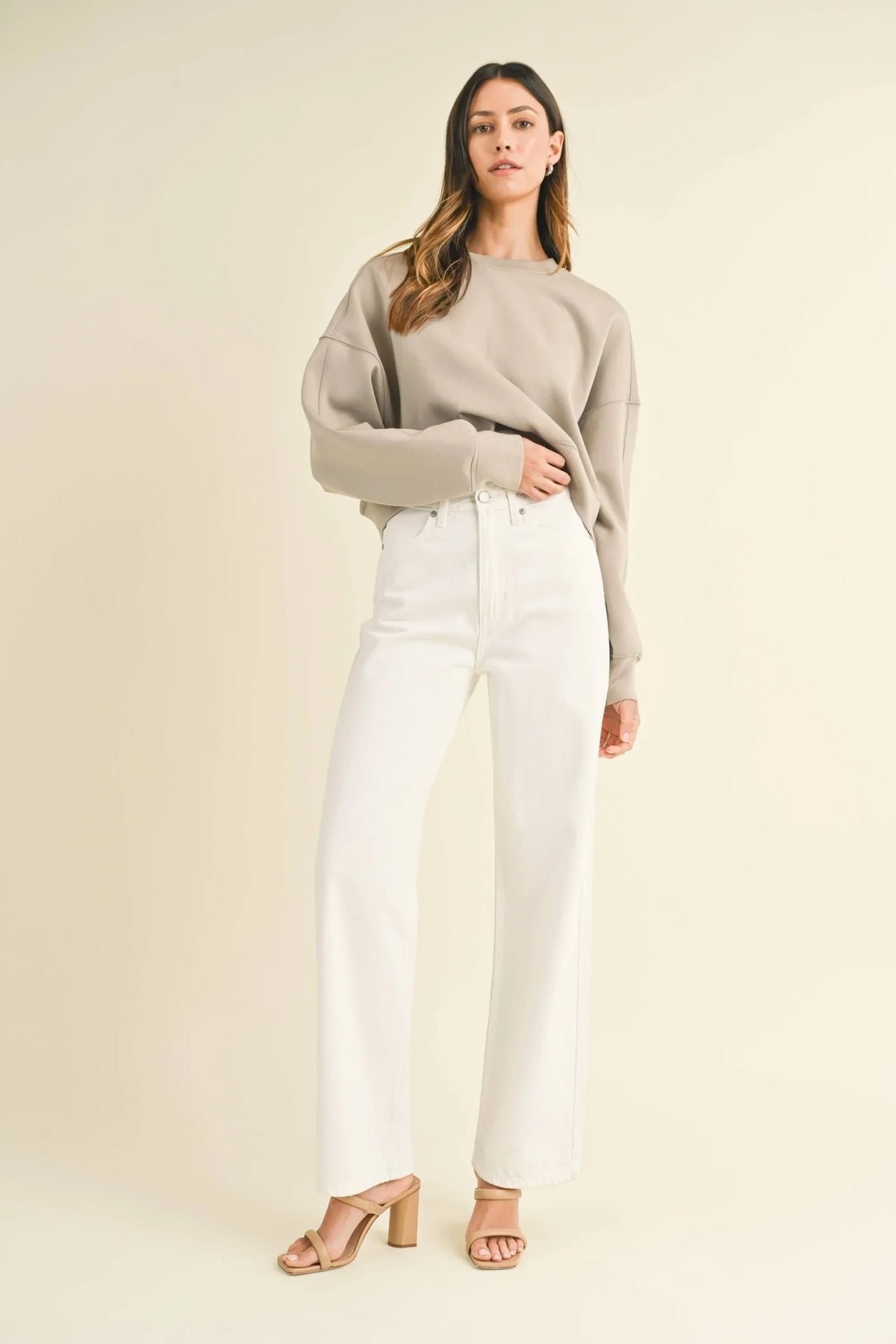 Person in beige sweater and white wide-leg pants showcasing light denim skater jeans